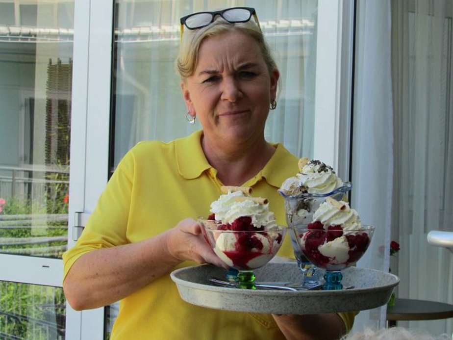 Eine Mitarbeiterin hält Eisbecher in der Hand.