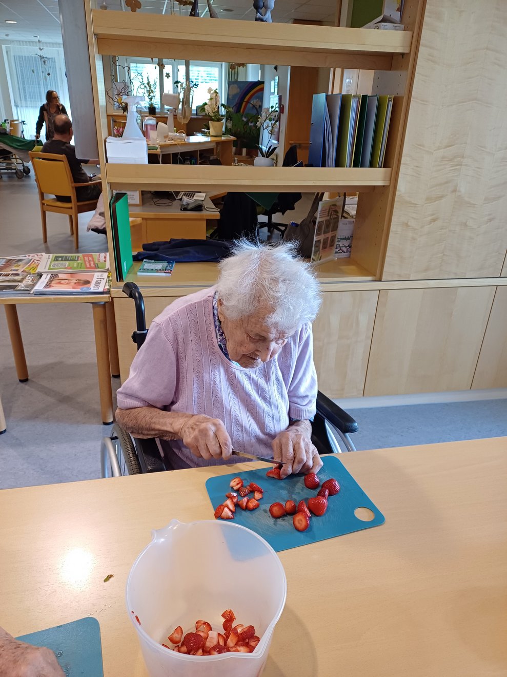 Bewohnerin beim Erdbeeren schneiden