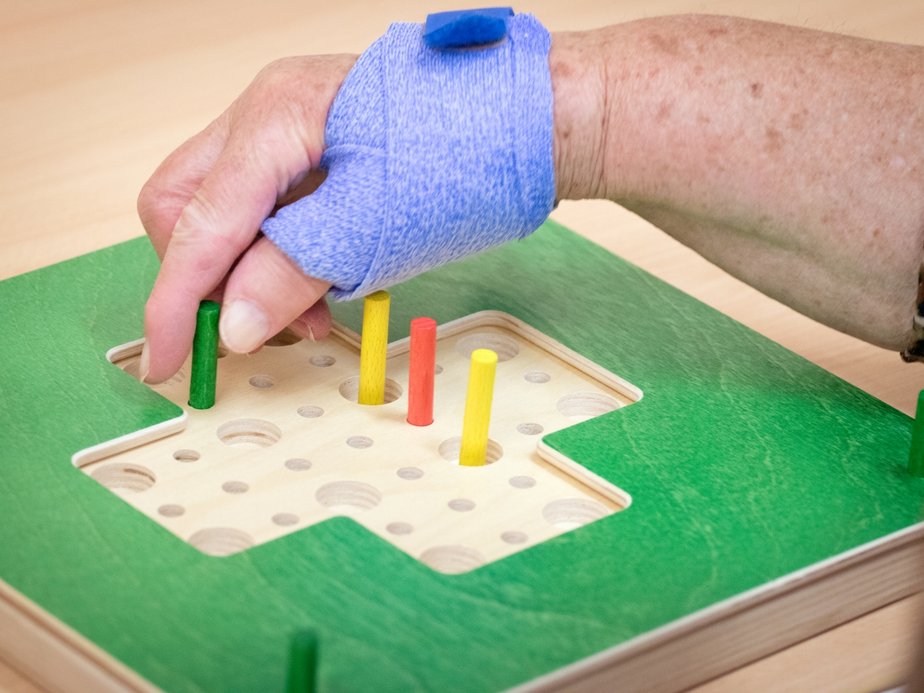 Ein Bewohner hält kleine Holzstäbe fest.