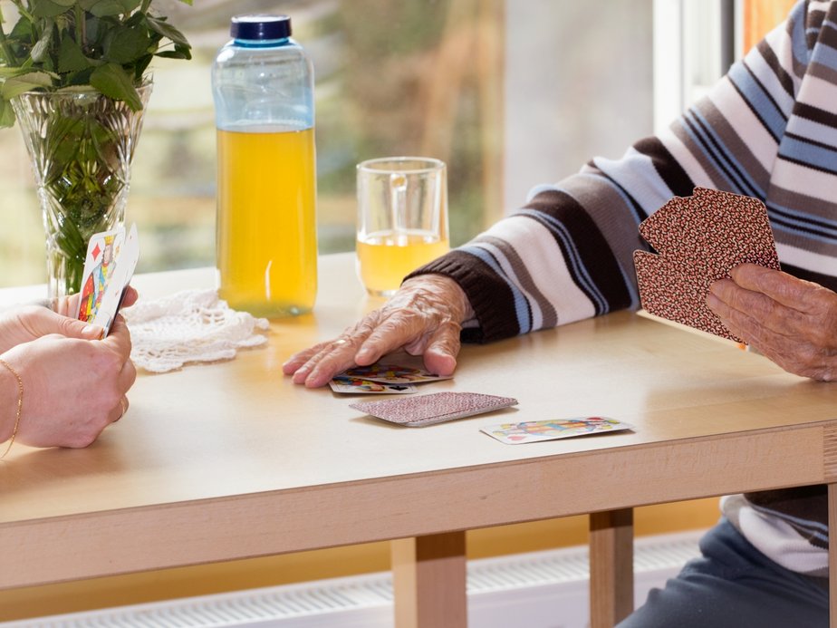 Eine Betreuerin und eine Bewohnerin spielen Karten.